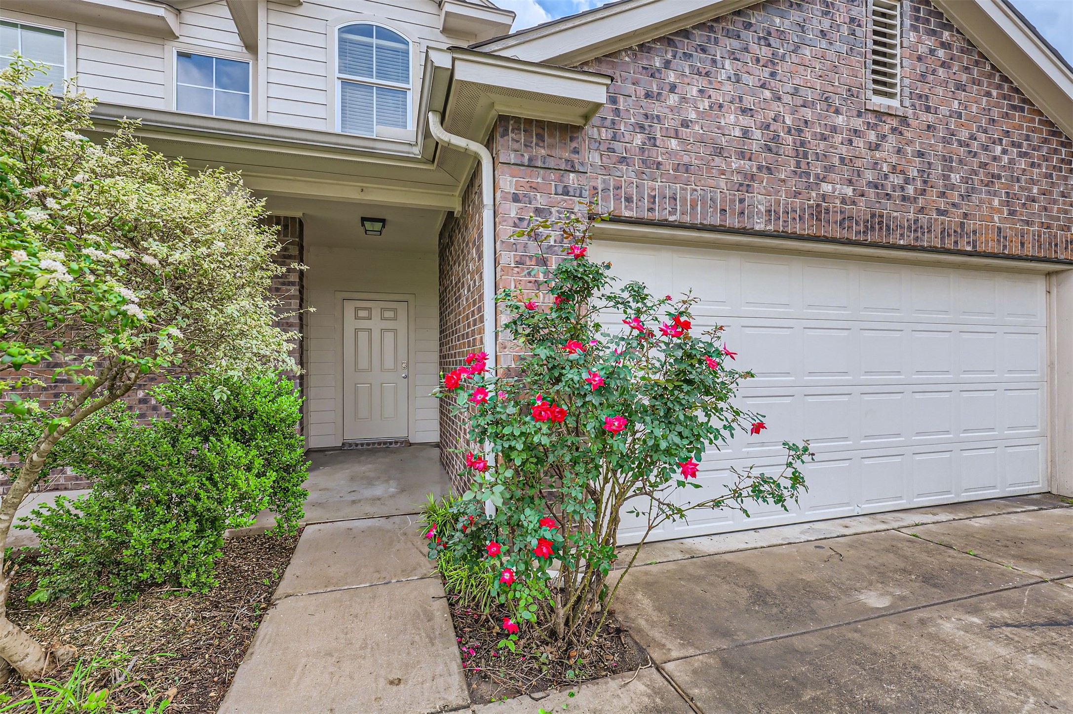 131 Lavaca Loop Hutto, TX 78634 - Photo 1 of 29 Brick and siding complement each other, with a two-car garage and a vibrant rose bush enhancing the home's approach.