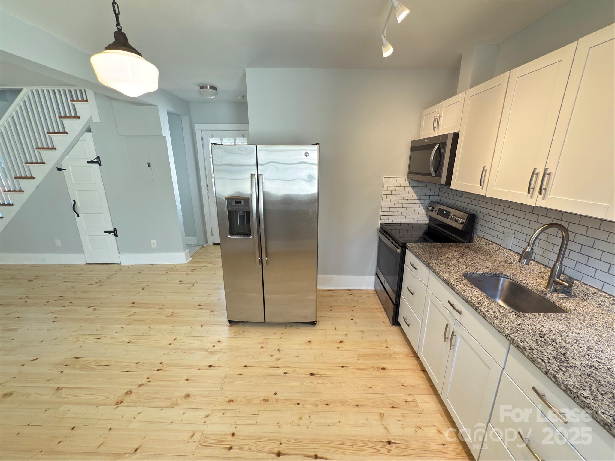 130 Maple Street Badin, NC 28009 - Photo 7 of 24 a kitchen with granite countertop a sink a counter top space cabinets and stainless steel appliances