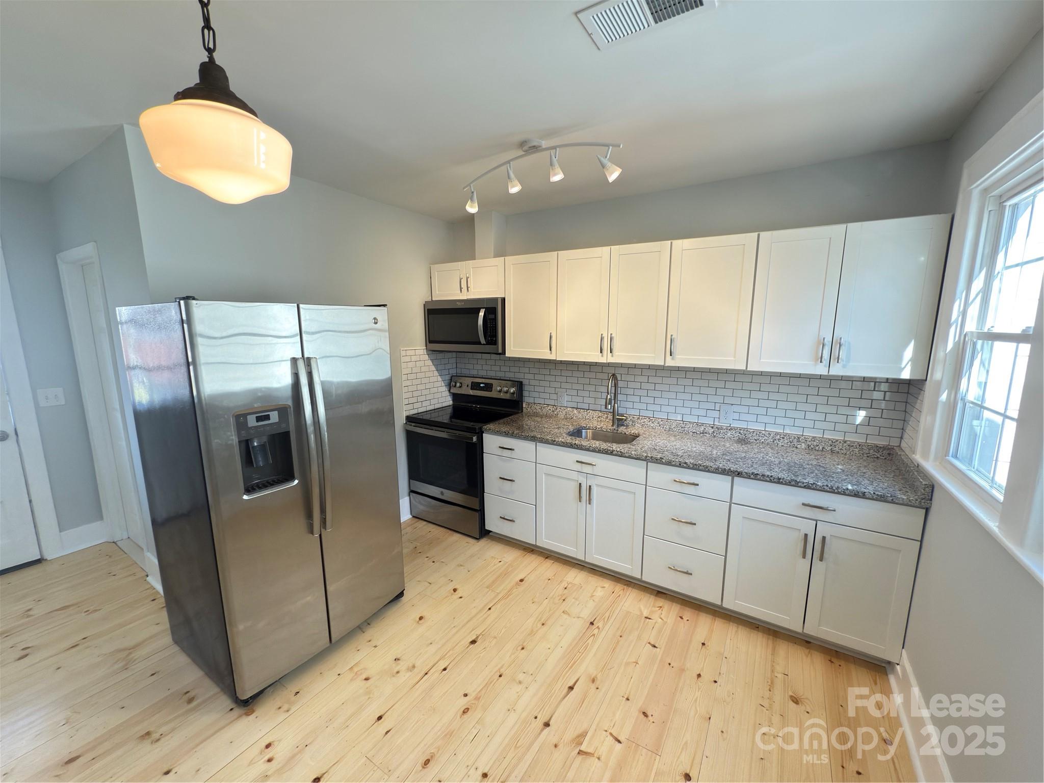 130 Maple Street Badin, NC 28009 - Photo 8 of 24 a kitchen with granite countertop a refrigerator a sink a stove a microwave and island
