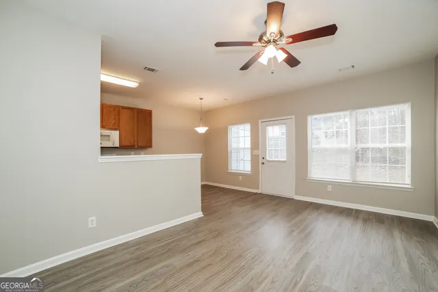 a view of an empty room with window and wooden floor
