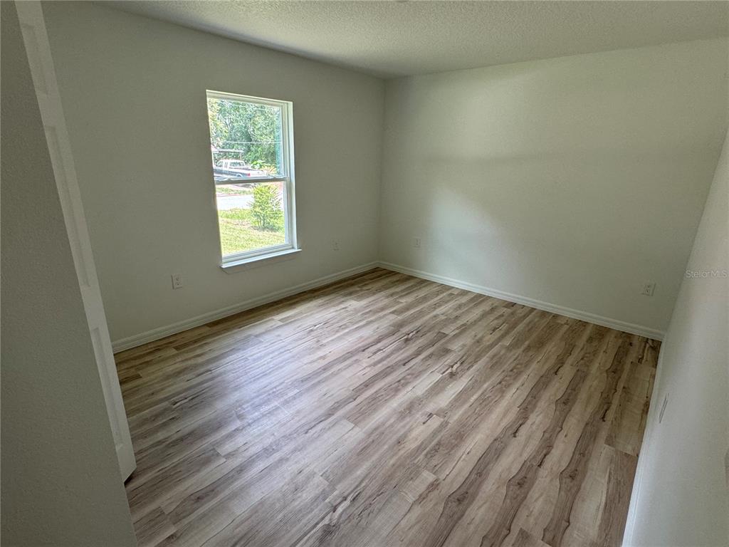 3244 East Deal Street Inverness, FL 34453 - Photo 7 of 17 an empty room with wooden floor and windows