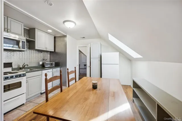 a kitchen with stainless steel appliances granite countertop a sink a stove a refrigerator and white cabinets with wooden floor