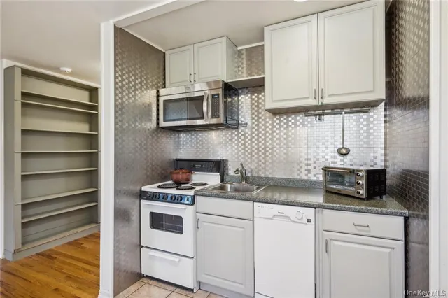 a kitchen with stainless steel appliances granite countertop white cabinets a microwave oven a sink and dishwasher