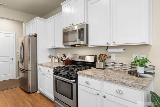 a kitchen with granite countertop a refrigerator stove and microwave