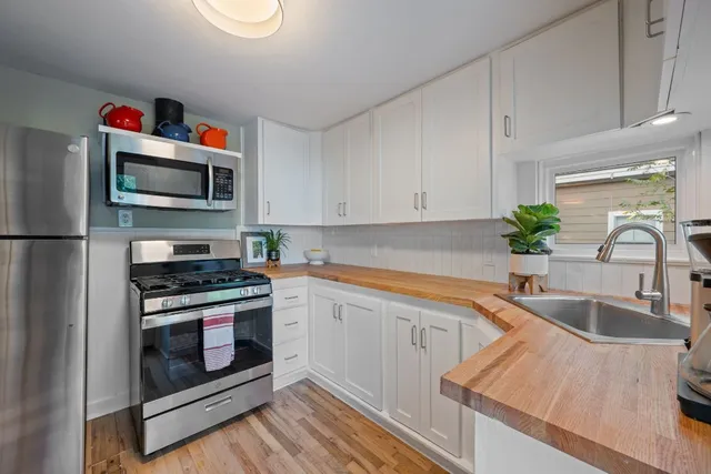 a kitchen with white cabinets a sink and a stove with wooden floor