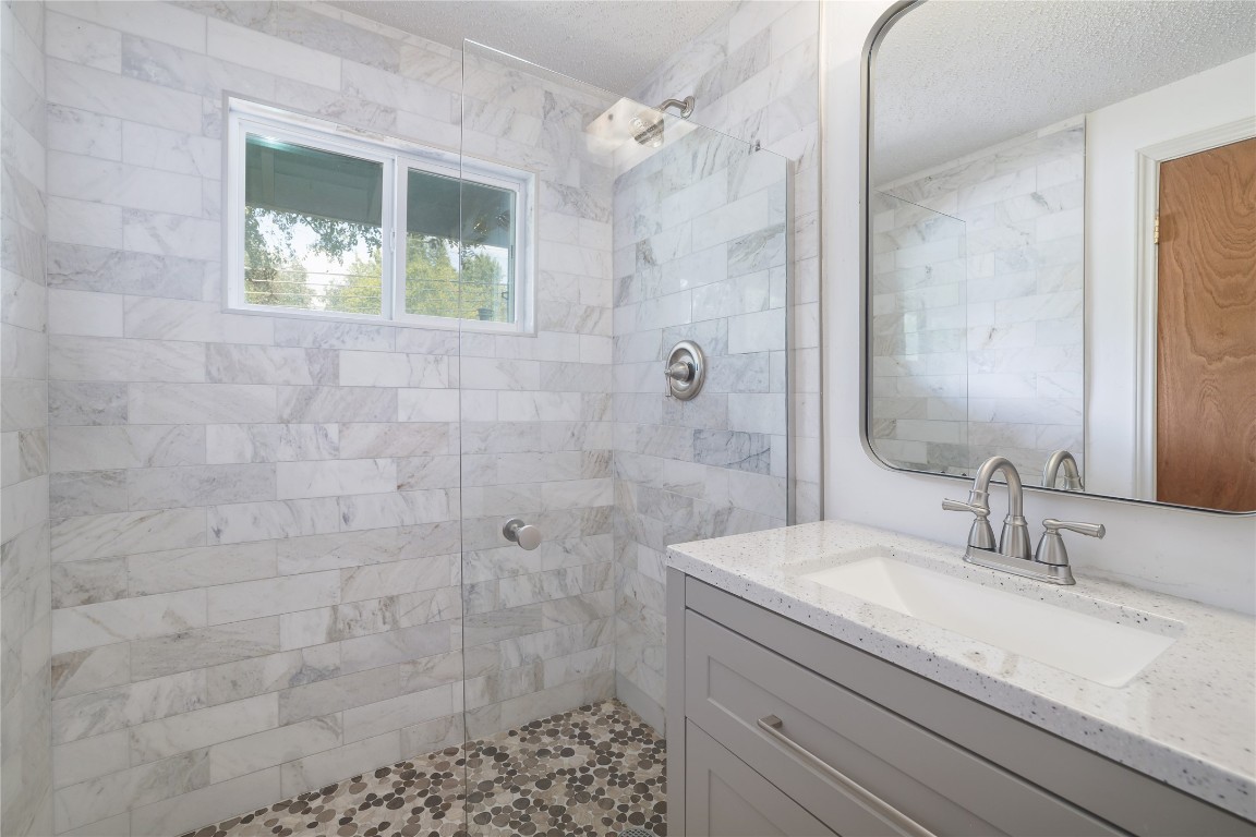 1818 Vance Circle Austin, TX 78701 - Photo 27 of 40 a bathroom with a granite countertop sink a shower and a mirror
