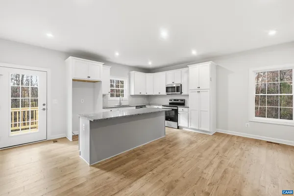 a kitchen with granite countertop a refrigerator and wooden floor