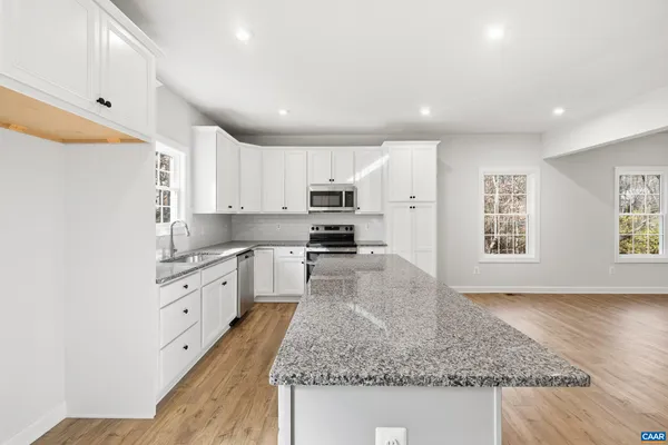 a kitchen with granite countertop a sink stainless steel appliances and white cabinets