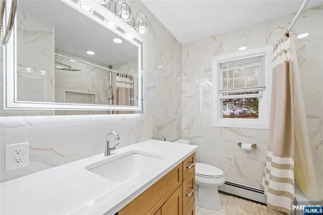 a bathroom with a sink a toilet a mirror and shower