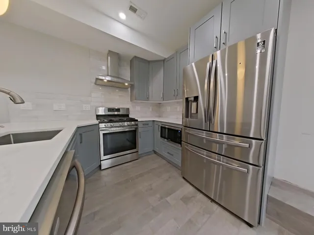 a kitchen with stainless steel appliances wooden floor and a refrigerator
