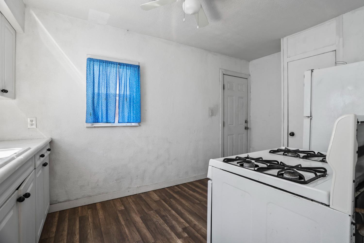 916 Elm Avenue Modesto, CA 95351 - Photo 41 of 52 Rear unit kitchen includes gas range, refrigerator space, cabinet storage, wood-look flooring, and exterior access.