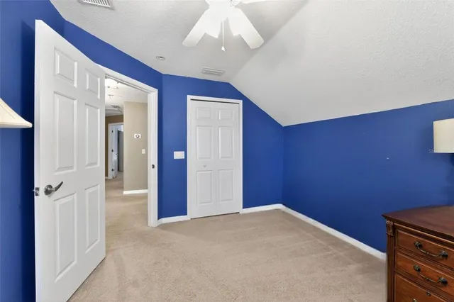 a spacious bedroom with a bed couch and a flat tv screen