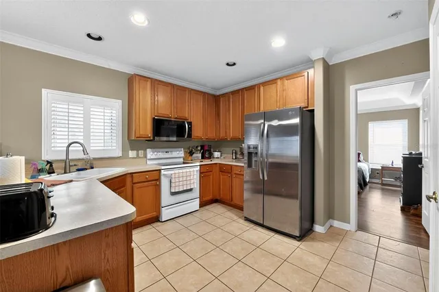 a kitchen with stainless steel appliances granite countertop a refrigerator oven a sink dishwasher a dining table and chairs with wooden floor