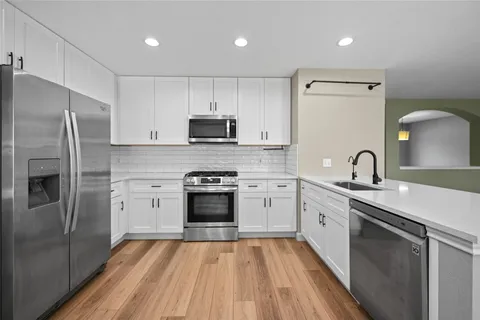 a kitchen with stainless steel appliances a sink cabinets and a stove top oven