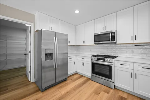 a kitchen with stainless steel appliances white cabinets a stove a microwave and a refrigerator