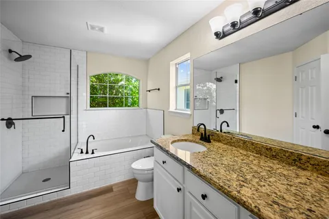 a bathroom with a granite countertop sink a toilet and shower