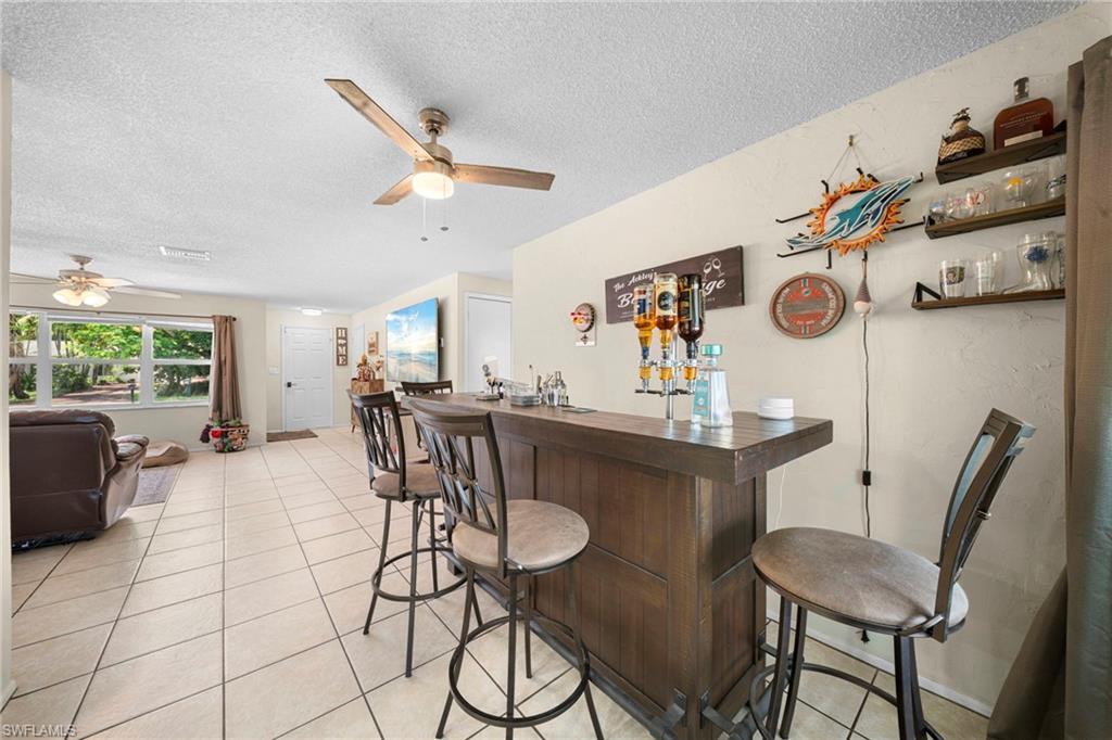 7289 Barragan Road Fort Myers, FL 33967 - Photo 11 of 18 Built-in bar with dark wood-finish cabinetry and countertop, accompanied by three bar stools