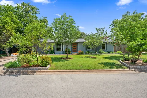 a front view of a house with a yard and potted plants