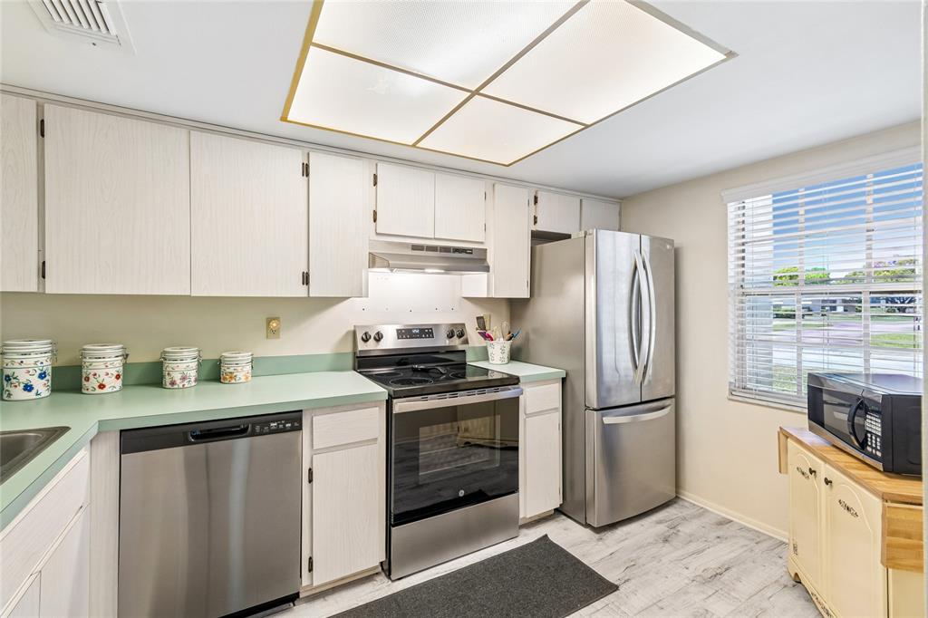 11340 Carriage Hill Drive, Unit 4 Port Richey, FL 34668 - Photo 2 of 36 a kitchen with stainless steel appliances white cabinets and a refrigerator