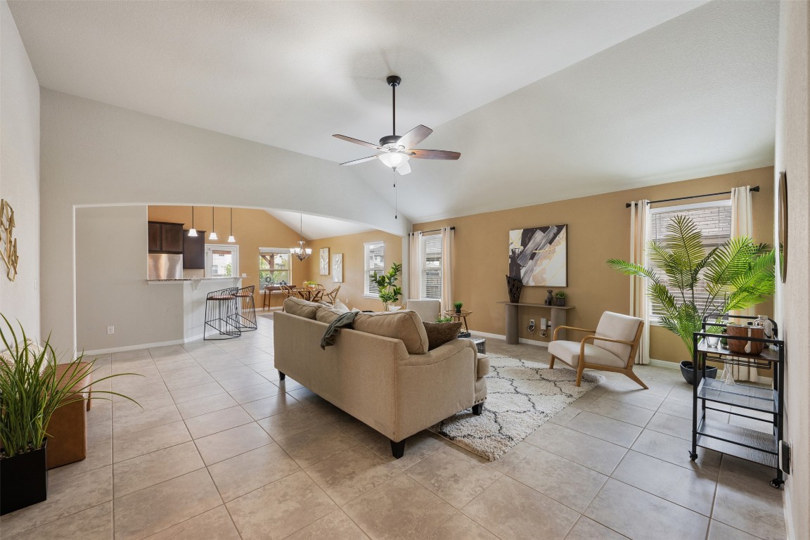 433 Rusk Bluff Avenue Leander, TX 78641 - Photo 3 of 22 Living area featuring vaulted ceiling, light tile patterned floors, ceiling fan, and a chandelier