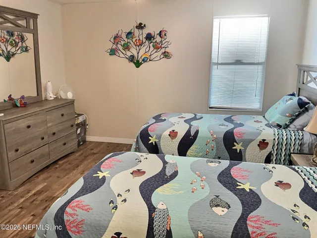 a bedroom with two bed and a painting on the wall