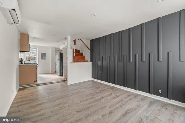 a view of a kitchen with wooden floor electronic appliances and staircase