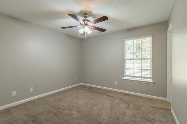an empty room with windows and fan