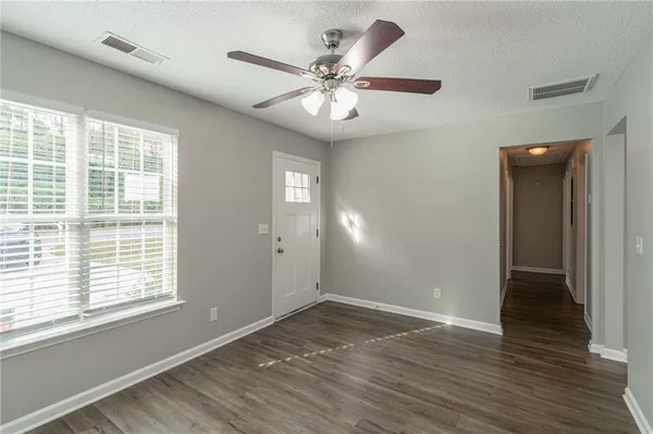 a view of an empty room with wooden floor and a window