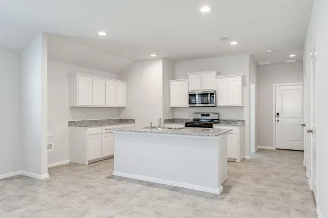 a kitchen with granite countertop white cabinets and stainless steel appliances