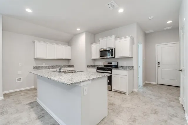 a kitchen with granite countertop white cabinets and white appliances