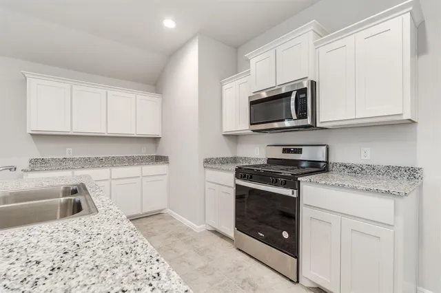 a kitchen with granite countertop white cabinets and stainless steel appliances