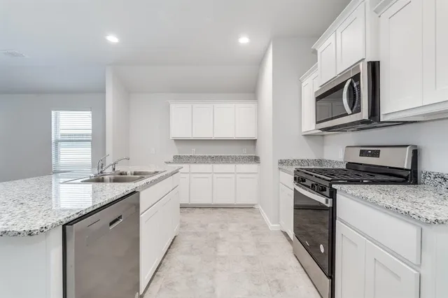 a kitchen with stainless steel appliances granite countertop a stove a sink and a microwave