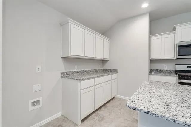 a kitchen with granite countertop a sink stove and microwave