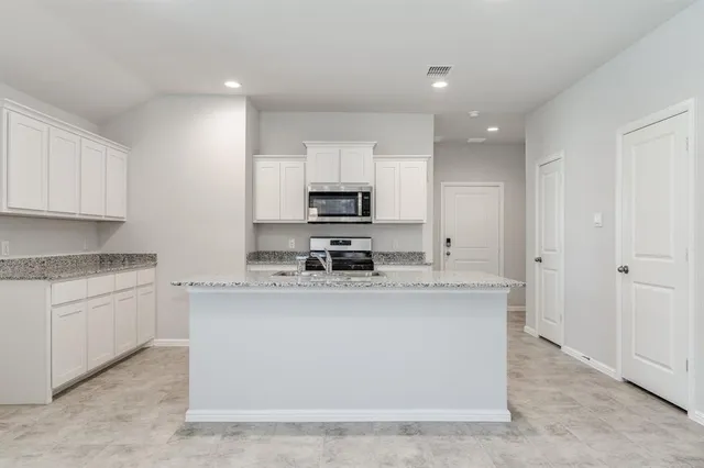 a kitchen with stainless steel appliances granite countertop a stove top oven a sink and a granite counter tops
