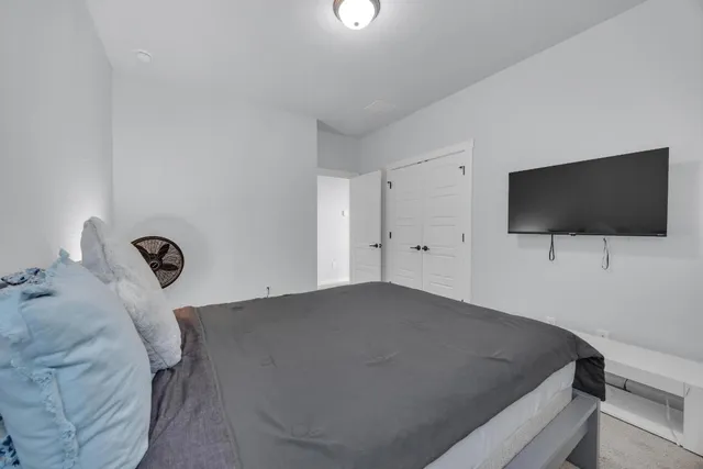 a bedroom with a bed and a flat tv screen on the dresser