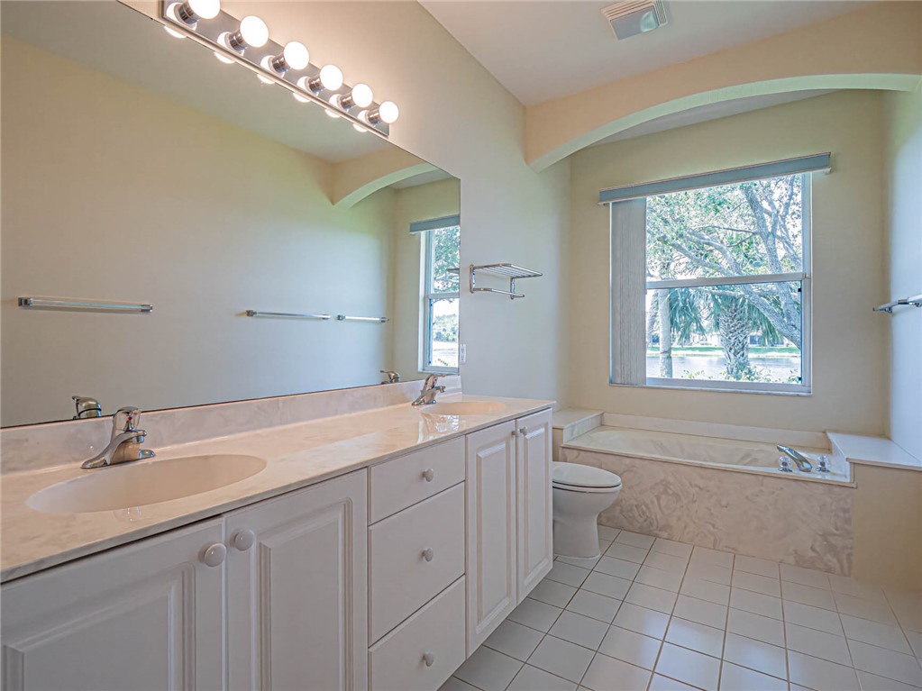 1422 Tradewinds Way Sebastian, FL 32958 - Photo 18 of 35 a spacious bathroom with a granite countertop sink a toilet and a mirror