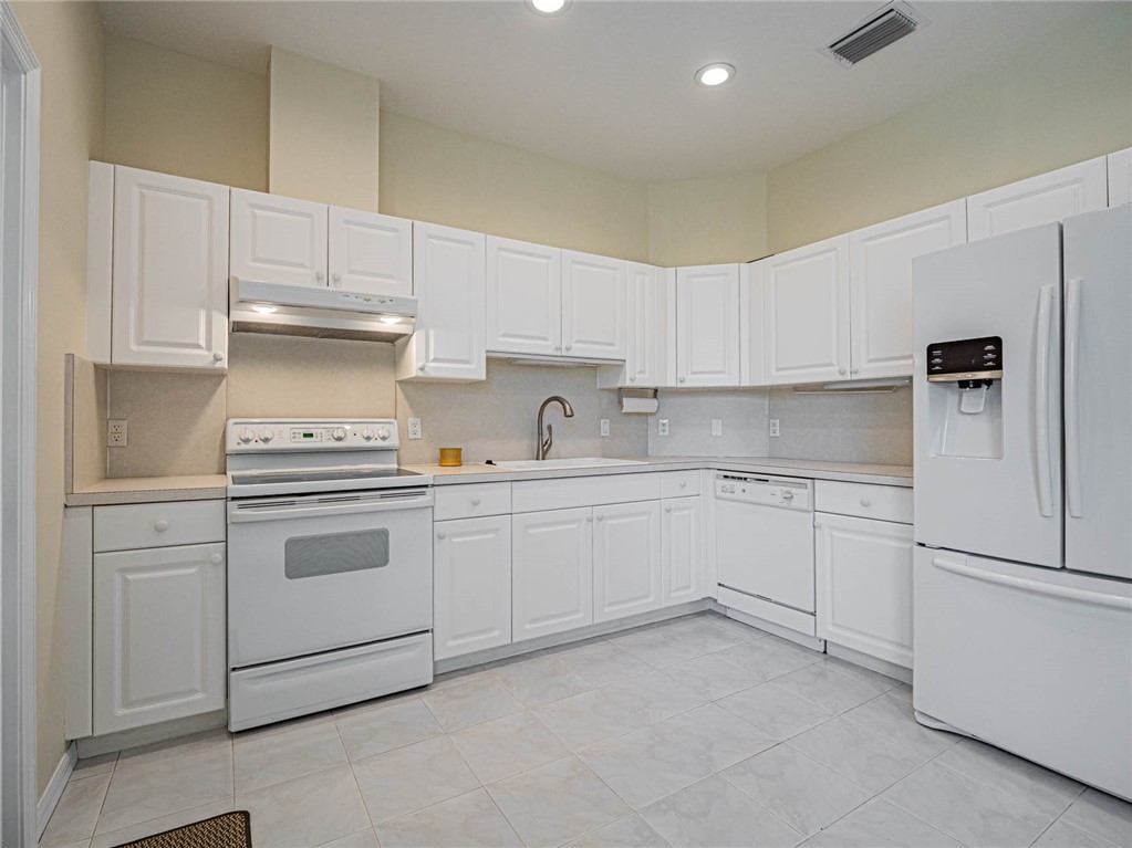 1422 Tradewinds Way Sebastian, FL 32958 - Photo 10 of 35 a kitchen with white cabinets and white appliances