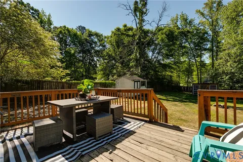 a view of a balcony with wooden floor outdoor seating and yard in the back