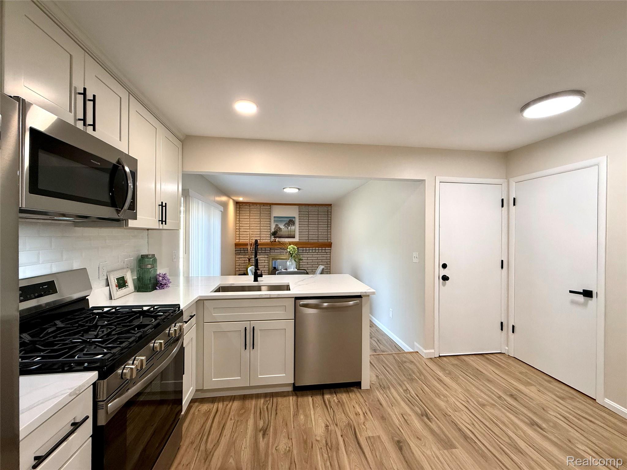 39909 Lynn Street Canton, MI 48187 - Photo 8 of 45 Modern kitchen featuring white shaker cabinetry with matte black hardware, stainless steel appliances, and wood-finish flooring