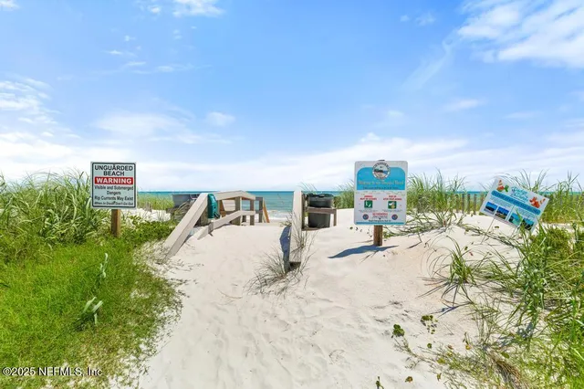 a view of swimming pool with lawn chairs plants and large tree