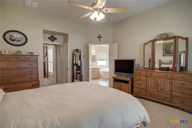 a bedroom with a bed and a flat tv screen on dresser