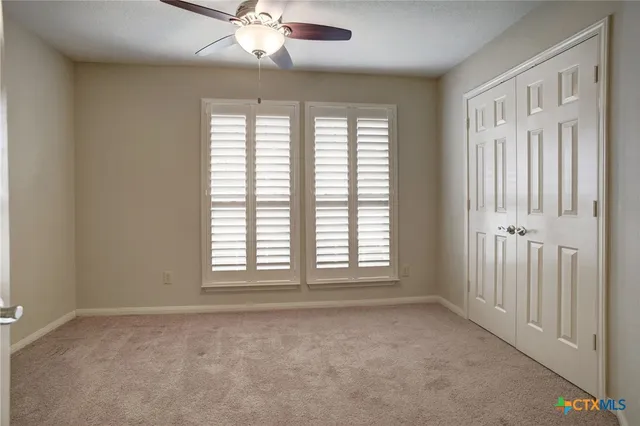 an empty room with chandelier fan and windows