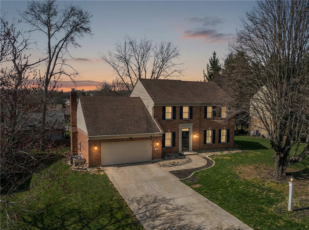 This classic brick residence features an attached garage and a well-maintained front yard.