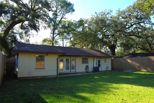 a view of a yard in front of a house with plants and large tree