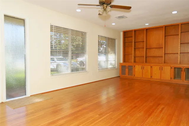 a view of an empty room with a window and wooden floor