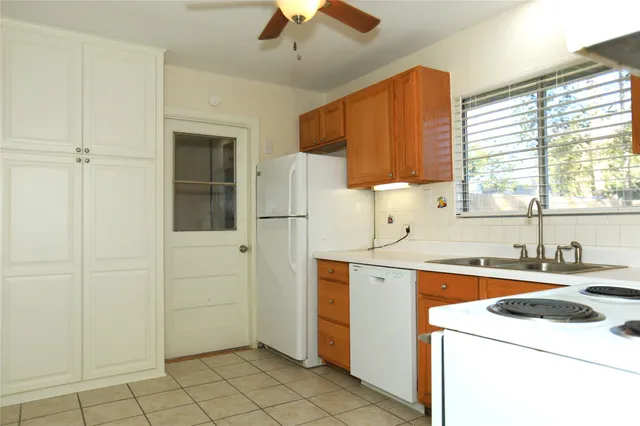 a view of a kitchen with a sink and dishwasher a refrigerator with white cabinets