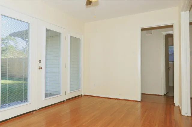 a view of an empty room with wooden floor and a bathroom
