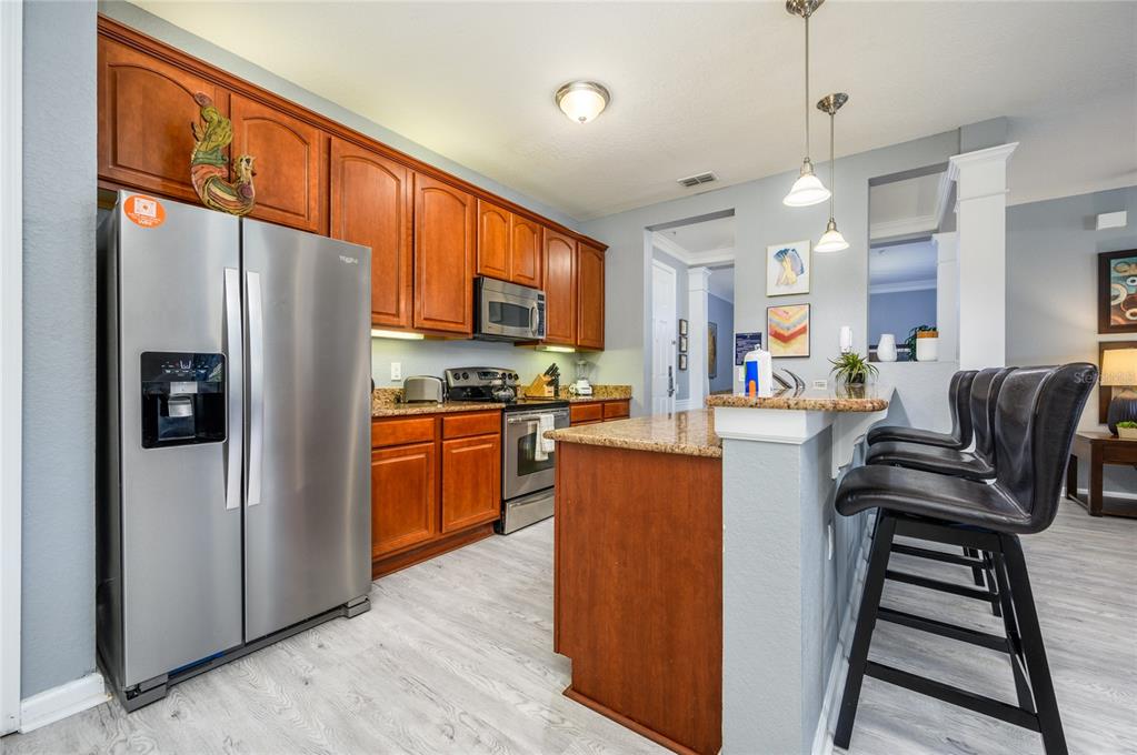 5012 Shoreway Loop, Unit 20507 Orlando, FL 32819 - Photo 13 of 49 a kitchen with stainless steel appliances granite countertop a refrigerator a stove top oven a sink dishwasher a dining table and chairs with wooden floor