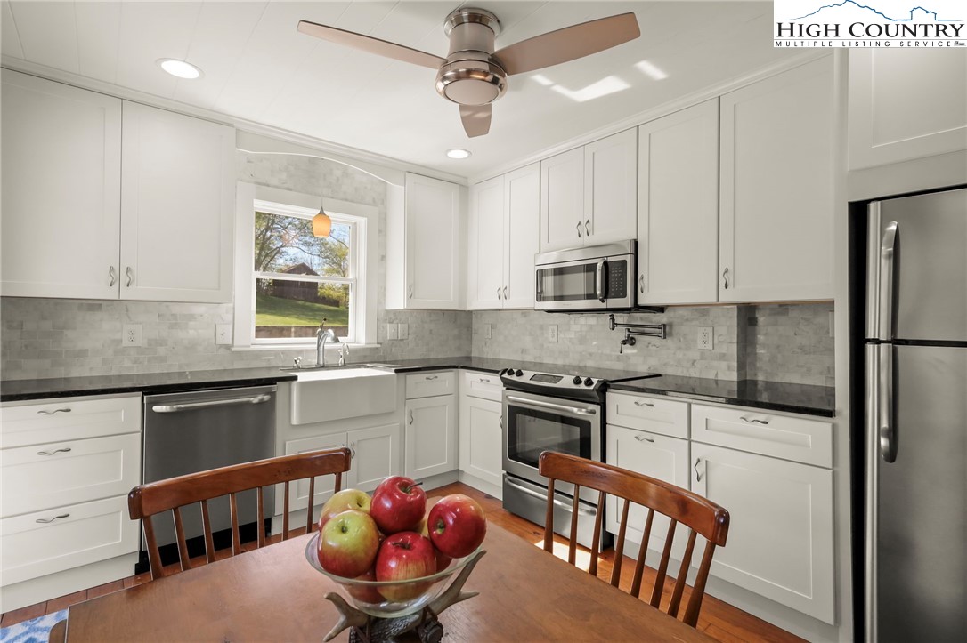 326 Ransom Street Blowing Rock, NC 28605 - Photo 8 of 25 a kitchen with stainless steel appliances granite countertop a stove a sink dishwasher a refrigerator with white cabinets and wooden floor