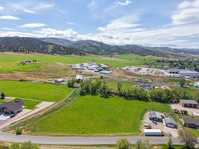 94 Spring Canyon Road Coalville, UT 84017 - Photo 19 of 50 Expansive green acreage featuring a paved road frontage, established residential structures, and distant mountains